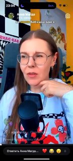 Кадр из вертикального видео: женщина в очках говорит в микрофон на фоне ярких стикеров и наложенного текста, иллюстрация обсуждения ИИ-креативов.