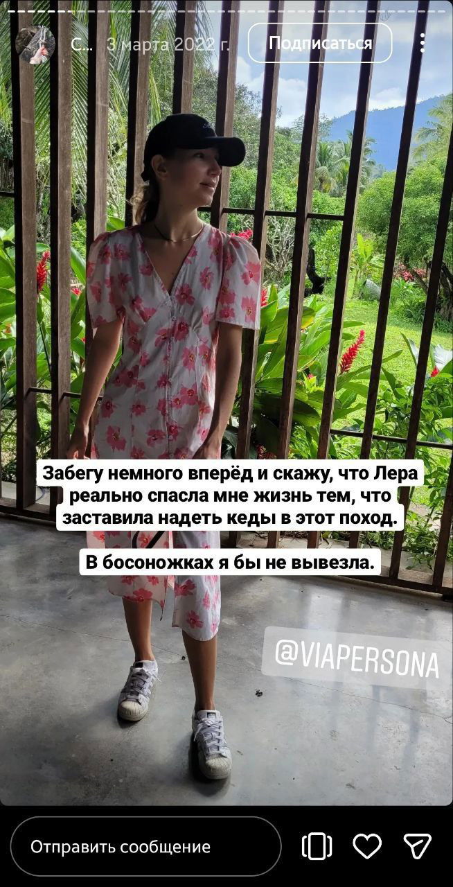 Девушка в летнем платье и кроссовках на веранде резорта, в бейсболке на фоне зелёного сада и гор — кадр перед походом к реке и водопадам.