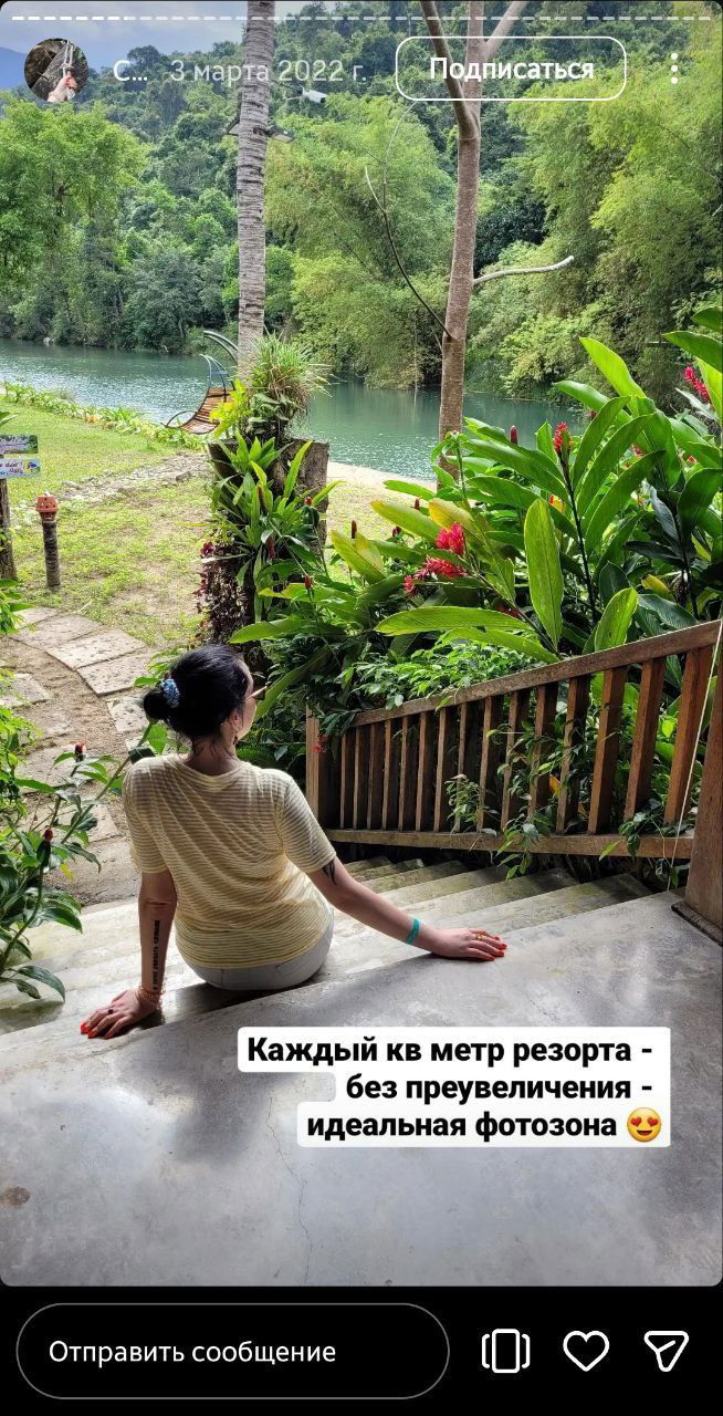 Женщина сидит на ступенях у реки и смотрит на изумрудную воду, вокруг тропическая растительность, фотозоны и уютные уголки резорта у берега.