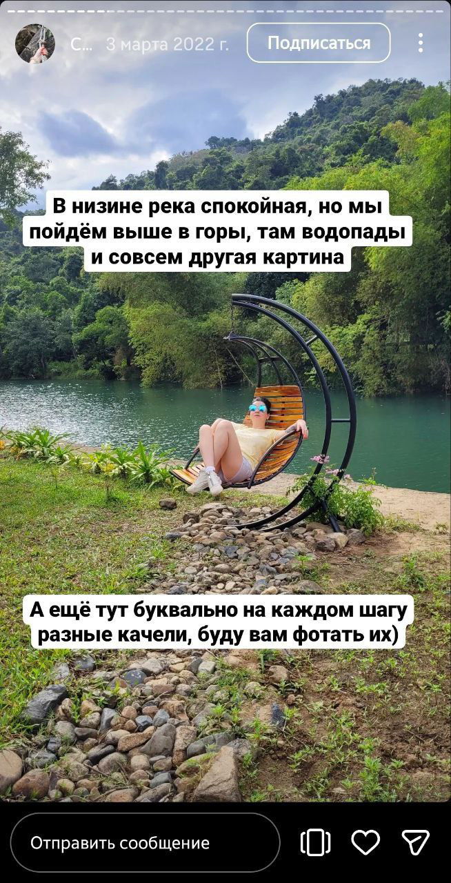 Женщина в солнцезащитных очках лежит на подвесном кресле у реки, перед ней спокойная зелёная вода, палисадники и горы на горизонте — кадр отдыха перед подъёмом.