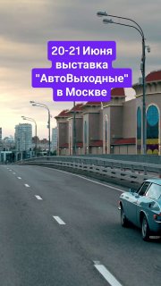 Ретро-автомобиль едет по широкой дороге в городской среде рядом с архитектурными зданиями — фото рекламного кадра анонса выставки «АвтоВыходные» в Москве.