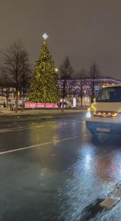 Ночной кадр: автовоз с автомобилями у ёлки на мокрой дороге в Москве, отражения в лужах, движение по Садовому.