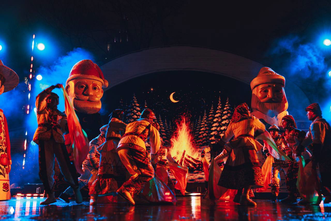 Танцы и массовая сцена спектакля у изображения большого костра и ночного пейзажа — живописная постановка по мотивам «12 месяцев».