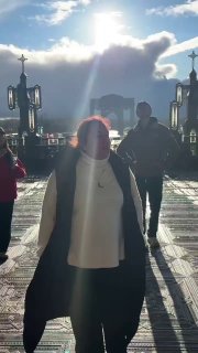 Силуэт женщины на фоне яркого солнца и гаваней света у входа в храм: игра света и тени, эмоциональный кадр с людьми, уходящими в перспективу площади.