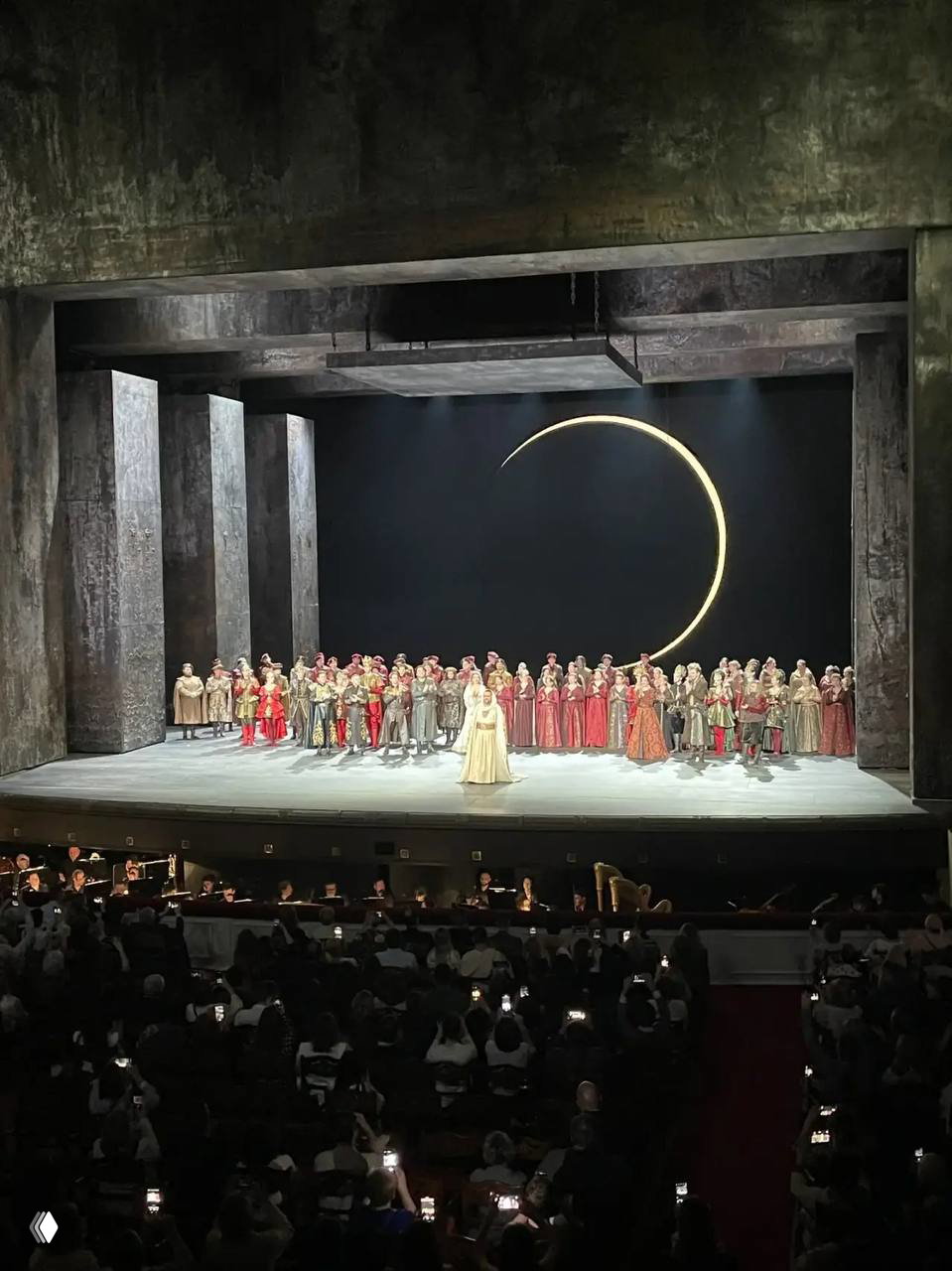 Интерьер Большого театра: роскошная люстра и ряды лож, на переднем плане — программка спектакля «Отелло» в руках посетителя.