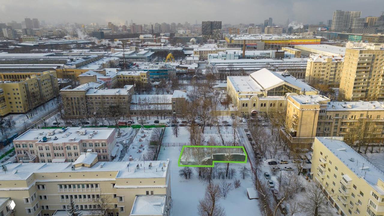 Аэрофотосъёмка участка у метро «Авиамоторная» зимой: очерченный зелёной линией земельный участок среди жилых и производственных зданий.