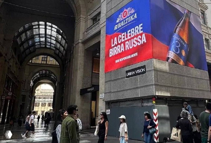 Угловой фасадный экран с рекламой «Балтика 3» и надписью на итальянском 'La celebre birra russa' в городской пешеходной зоне.