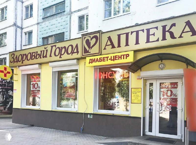 Фасад аптеки сети «Здоровый город» с желтой вывеской «Аптека», табличкой «Диабет‑центр», входной группой и рекламными наклейками о скидках на стеклах.