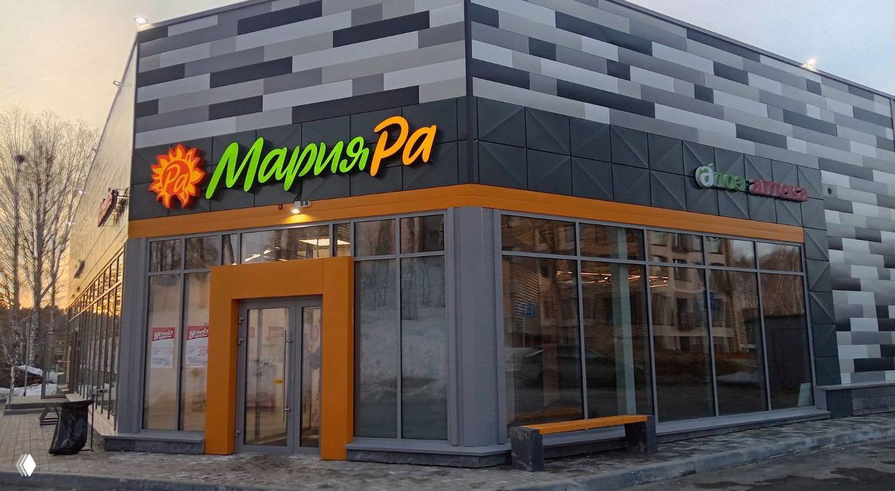 Фасад магазина «Мария‑Ра» в сибирском городе зимой: яркая вывеска над входом, большие стеклянные витрины и современная отделка.