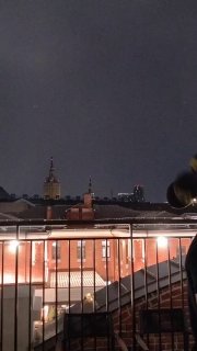 Ночной кадр с террасы: огни ресторанов и крыши зданий на фоне тёмного неба, вид приблизительно того же района Москвы.