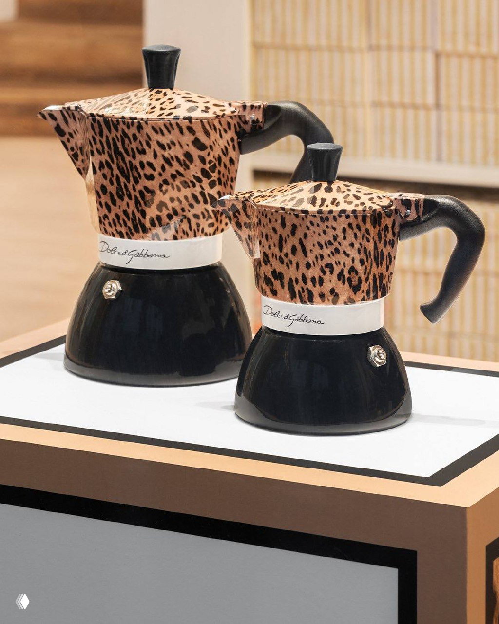 Крупный план двух мока‑кофеварок в леопардовом принте Dolce&Gabbana x Bialetti на белом столе, видна подпись Dolce&Gabbana на корпусе