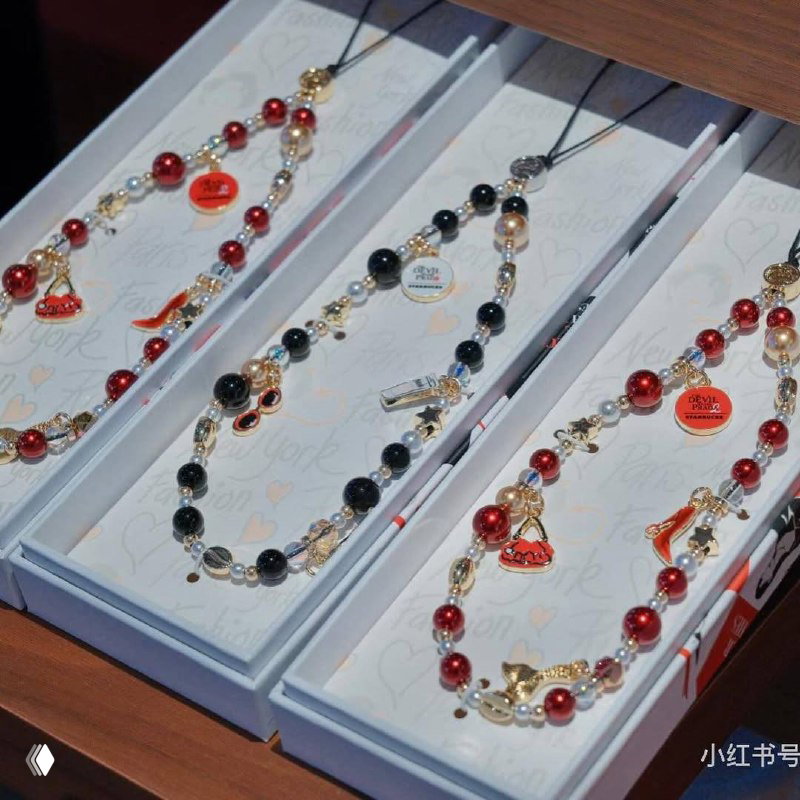 Наборы бижутерии и ожерелий в подарочной упаковке с красно‑чёрными бусинами и подвесками, часть коллекции мерча с брендингом фильмов.