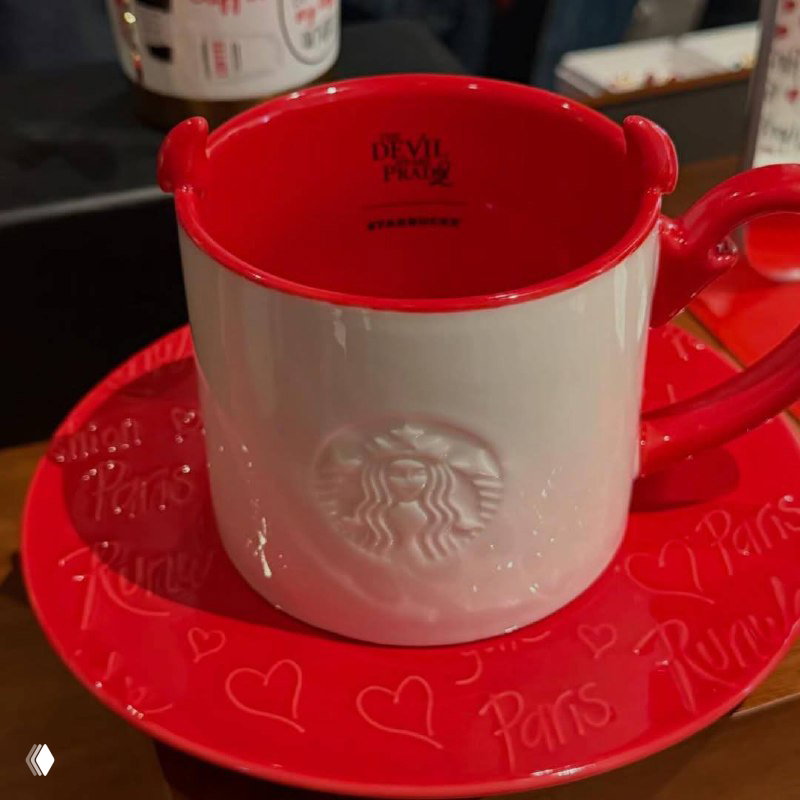 Четыре кружки на красном лотке с графичным принтом и маленькими декоративными «рогами» у края, композиция на прилавке магазина.