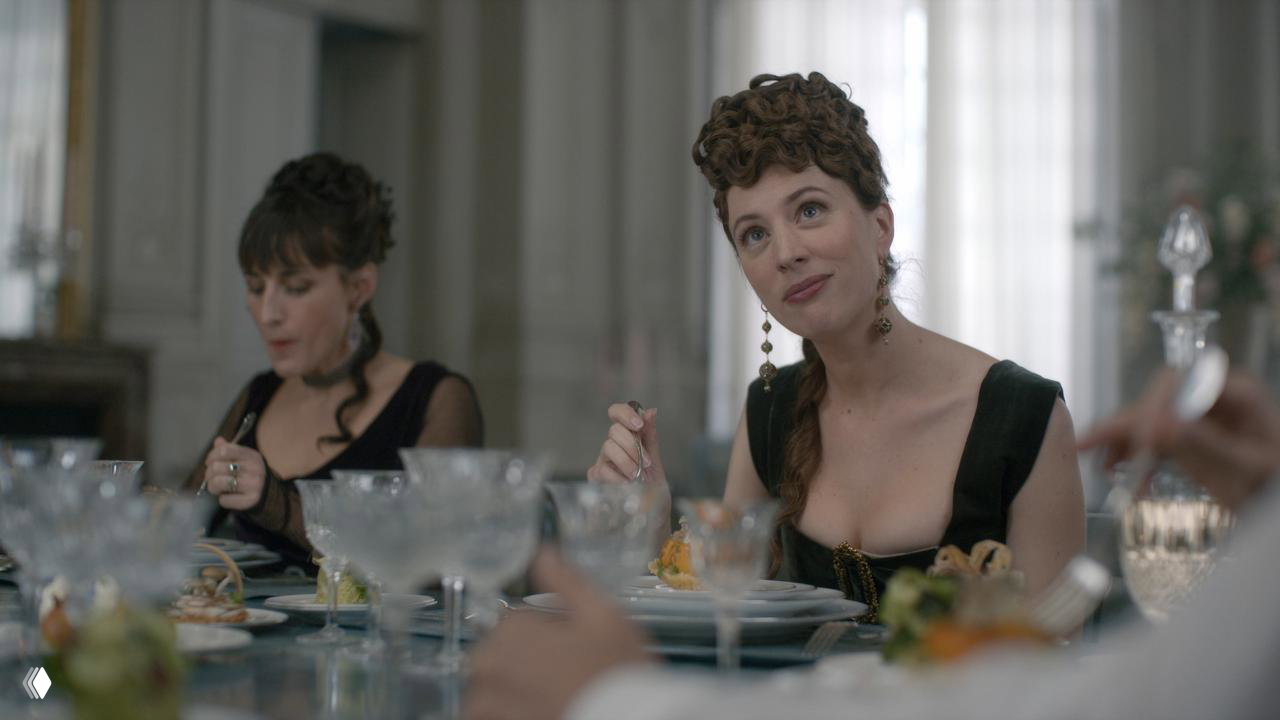 Банкетная сцена: гости за столом в исторических костюмах, сервировка и тонкая эстетика подачи — внимание к деталям интерьера и блюд.