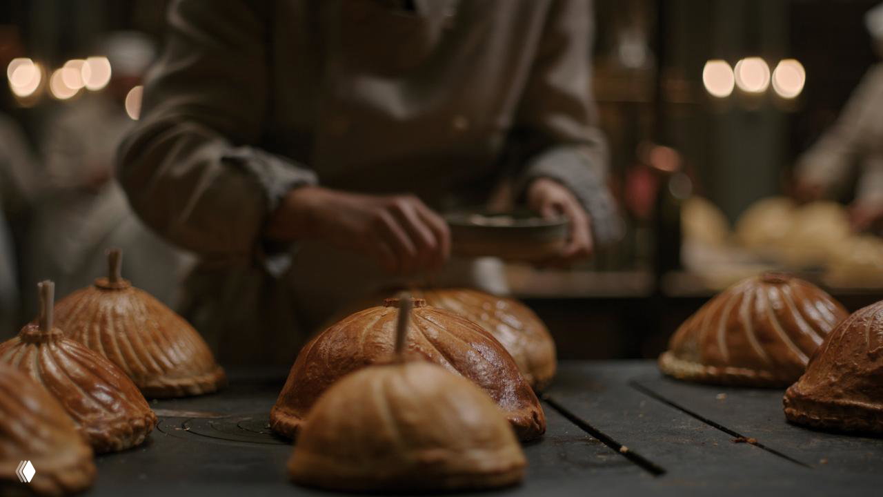 Крупные батоны выпечки или закрытые пироги на противне — текстура корки и тёплый свет выпечки в старой печи.