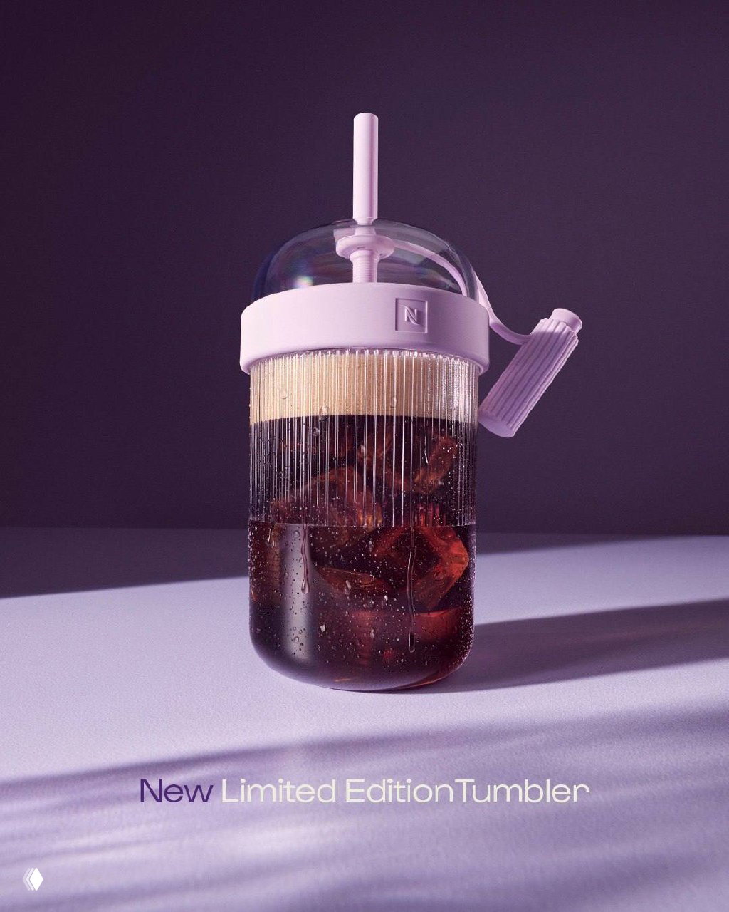 Крупный план лимитированного тумблера Nespresso с прозрачной купольной крышкой, видны лёд, конденсат и детализация пластины — студийная подача продукта.