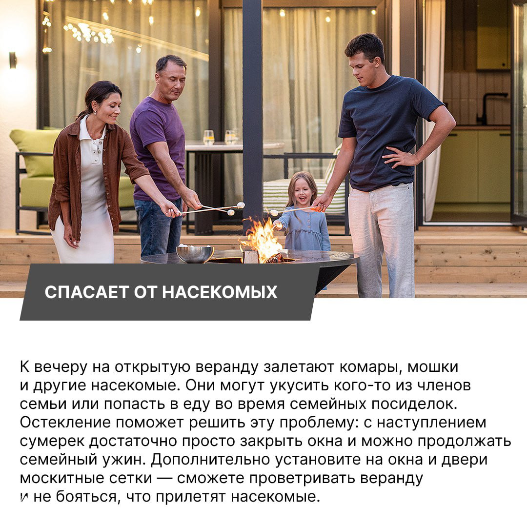 Семья у огня на террасе у остеклённой веранды: взрослые и ребёнок готовят еду на улице рядом с остеклённой частью дома вечером.