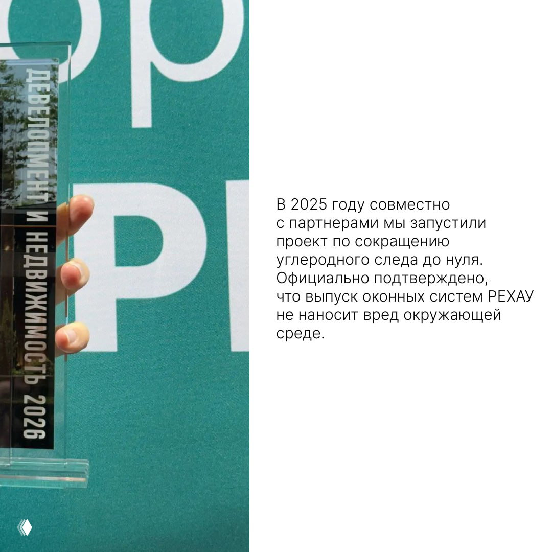 Ближайший план награды РЕХАУ с гравировкой «Девелопмент и Недвижимость 2026» на фоне фирменного баннера и текста о снижении углеродного следа