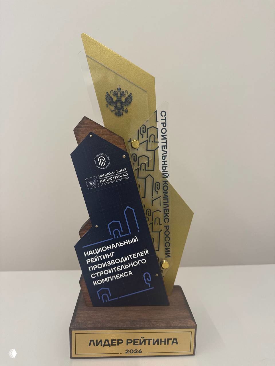 Крупный план статуэтки с надписью «Лидер рейтинга 2026», дизайн в золоте, дереве и тёмно‑синем оформлении — награда национального рейтинга производителей.