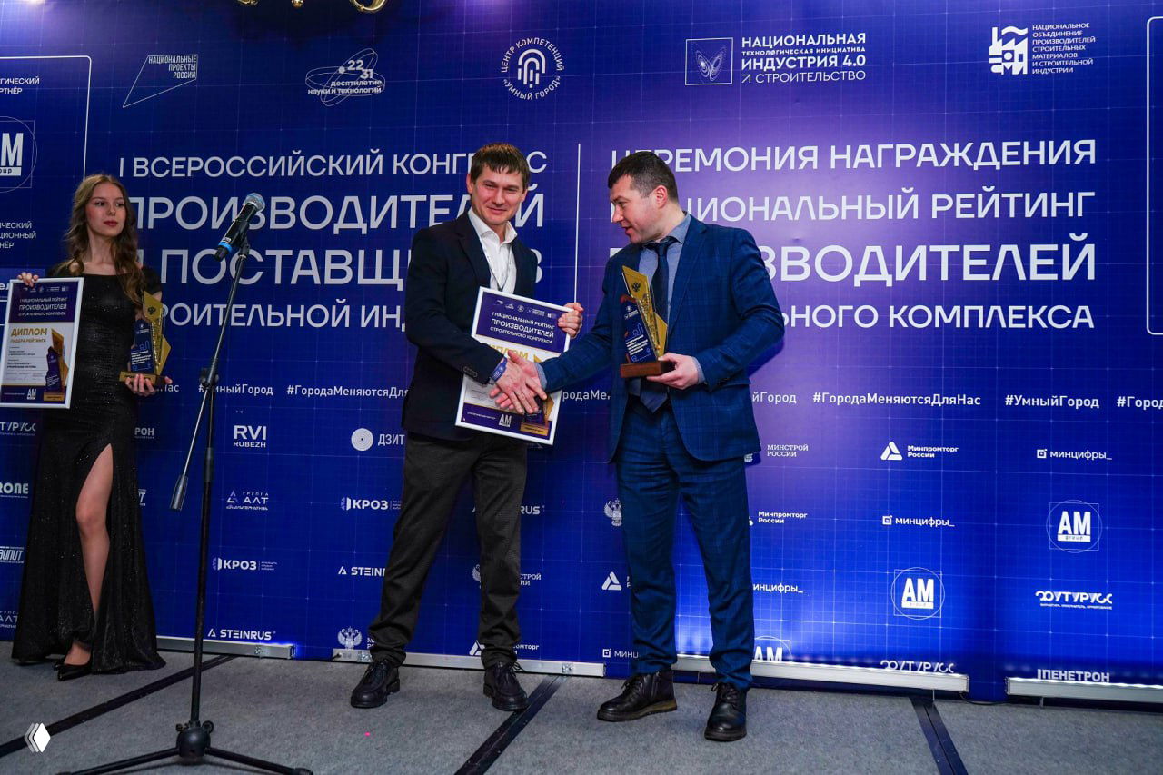 Момент вручения наград на сцене: два человека обмениваются поздравлениями, на фоне большой синей панели с названием конгресса и рейтинга.