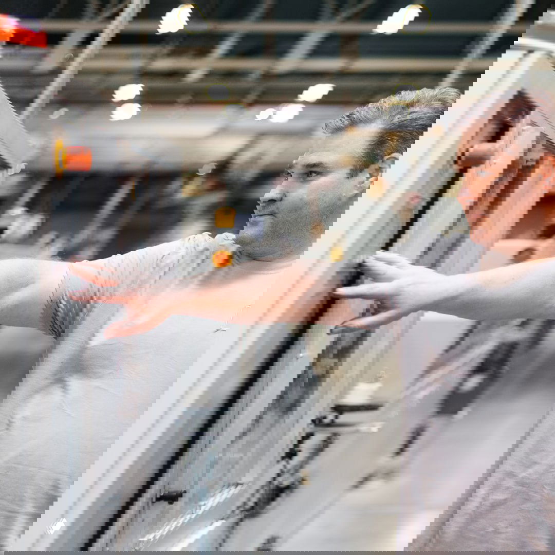 Оператор на производстве управляет панелью станка — кадр подчёркивает автоматизацию и технологичность процессов на предприятии РЕХАУ.