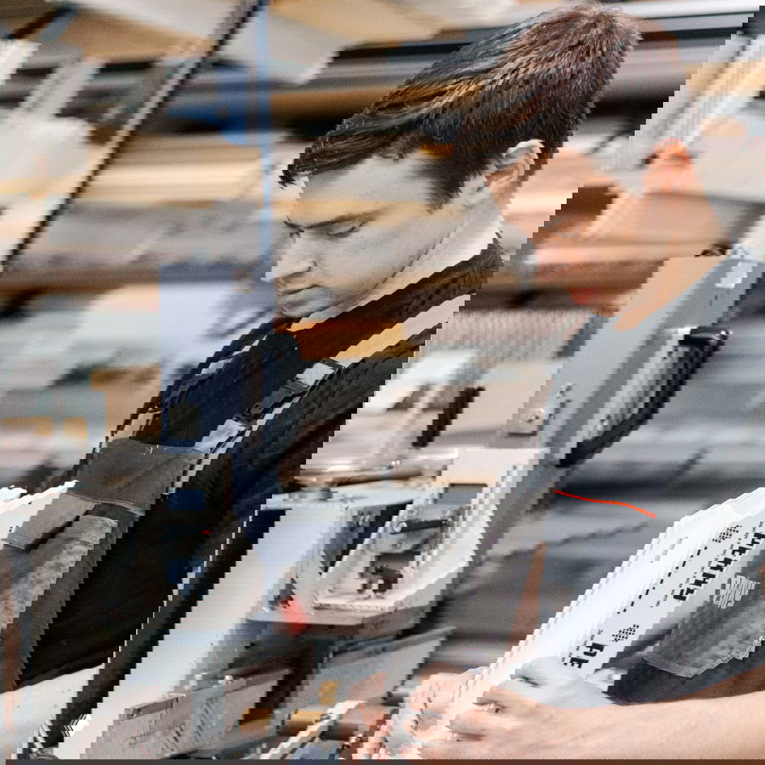 Специалист проверяет и держит фрагмент оконного профиля РЕХАУ в цехе — демонстрация производственного контроля и оригинальной маркировки.