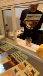 Небольшой торговый окошко Dip Daddy: продавец держит меню, на прилавке видна витрина с ассортиментом — кадр в движении и легкая размытость.