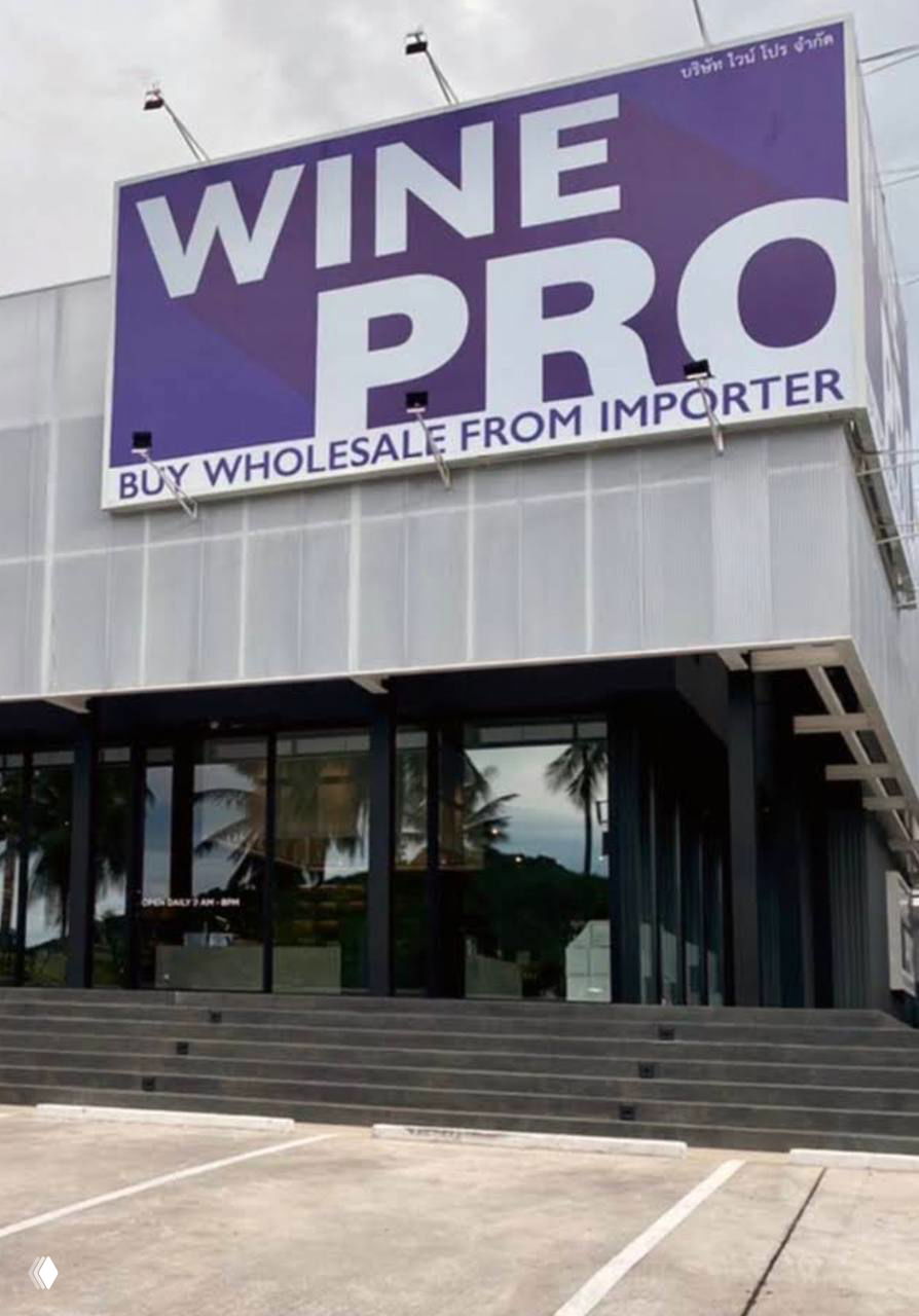 Фасад магазина Wine Pro с крупной фиолетовой вывеской — место покупки бургера на Самуи, видны ступени и стеклянный вход.