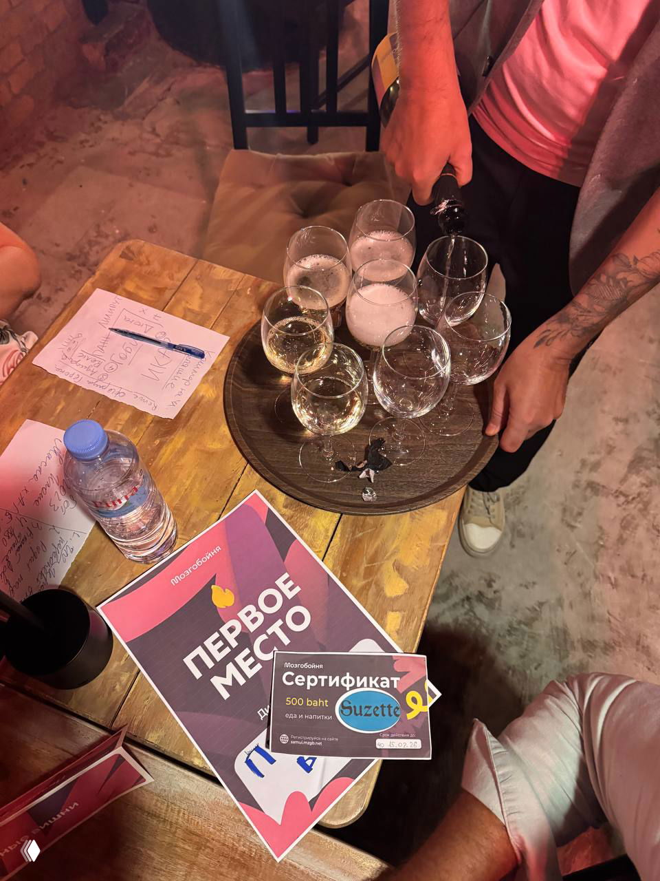 Поднос с бокалами и шампанским, на столе сертификат и листовка «Первое место» — кадр с викторины и награждения в Suzette.