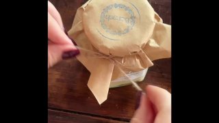 Крупный план рук, завязывающих бумагу и веревочку на банке с десертом; процесс упаковки показывает аккуратную подачу в банке в ларьке БОРЩ.