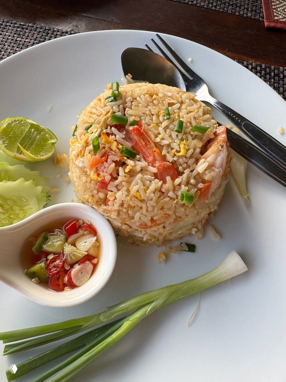 Тарелка с жареным рисом и крупными креветками, долька лайма, соус чили и зелёный лук на белой тарелке — пример домашней подачи блюда в новом кафе на Самуи.