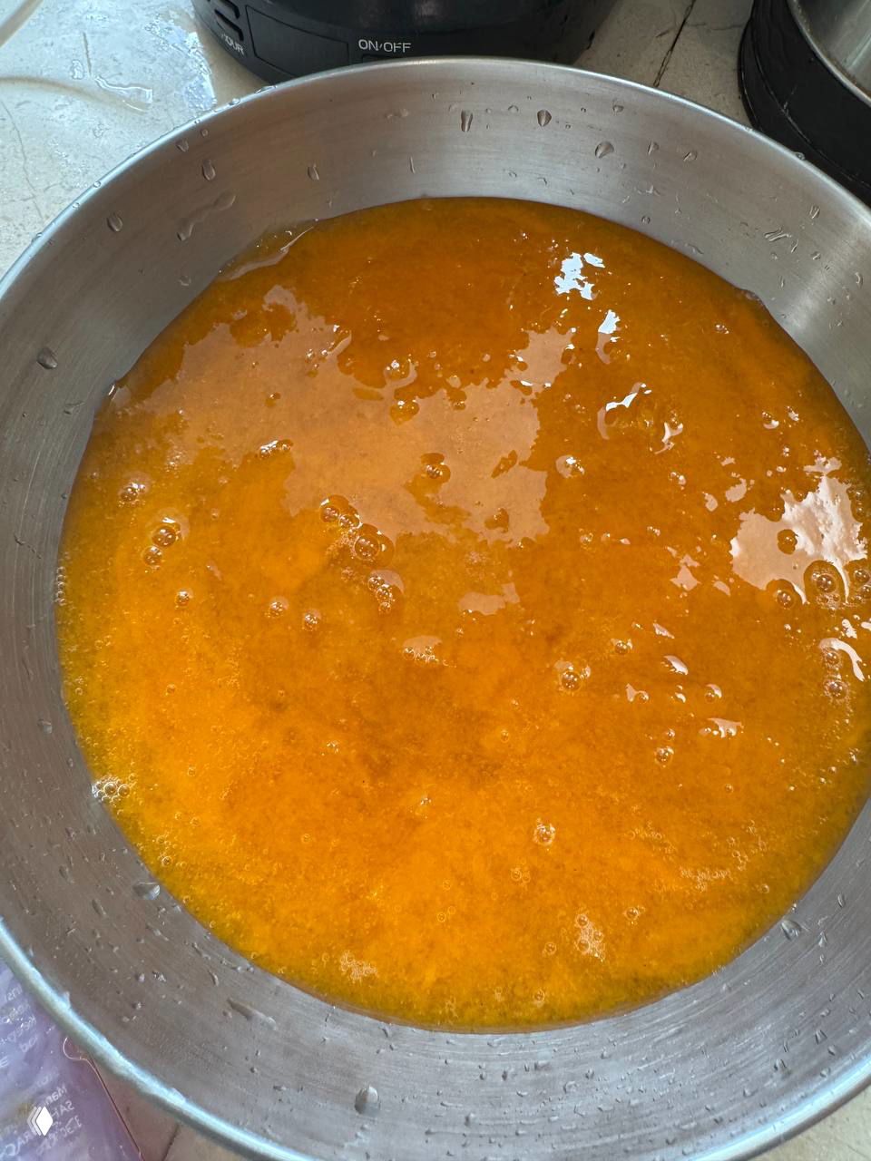 Миска с размороженным маракуйевым пюре оранжевого цвета, вид крупным планом: текстура пюре с маленькими пузырьками перед загущением тапиокой.