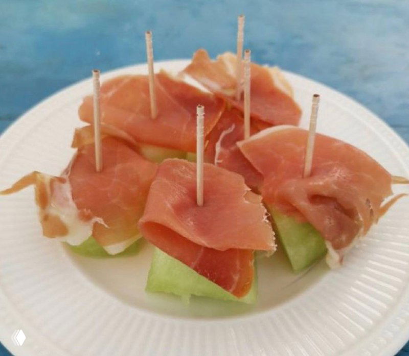 Кусочки светлой дыни, сервированные с ломтиками хамона на белой тарелке — визуализация сочетания «дыня + хамон», о котором пишет автор.