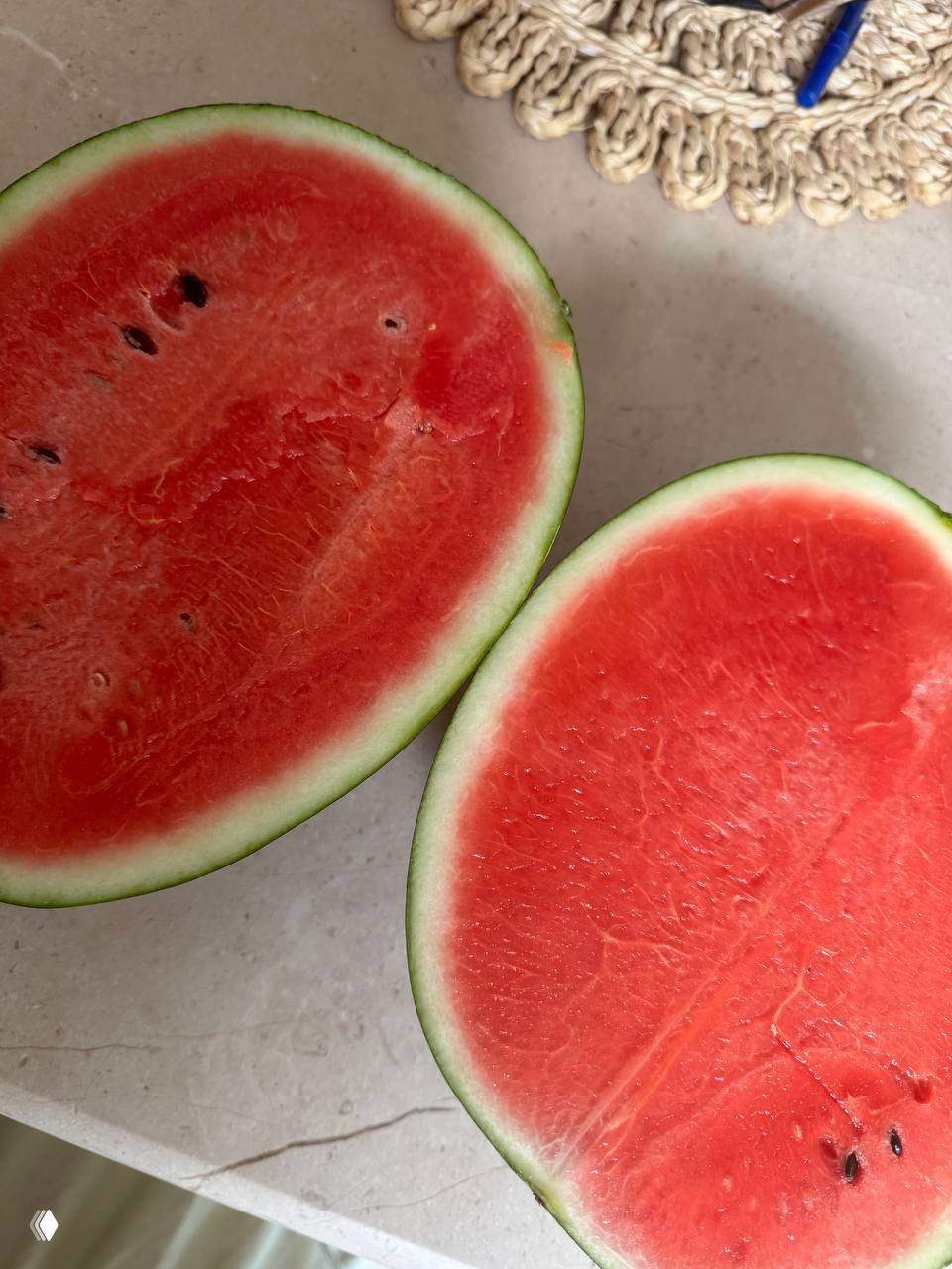 Разрезанный арбуз с ярко-красной мякотью и видимыми семенами; показана сочная текстура внутри, фото сделано на кухонной поверхности.