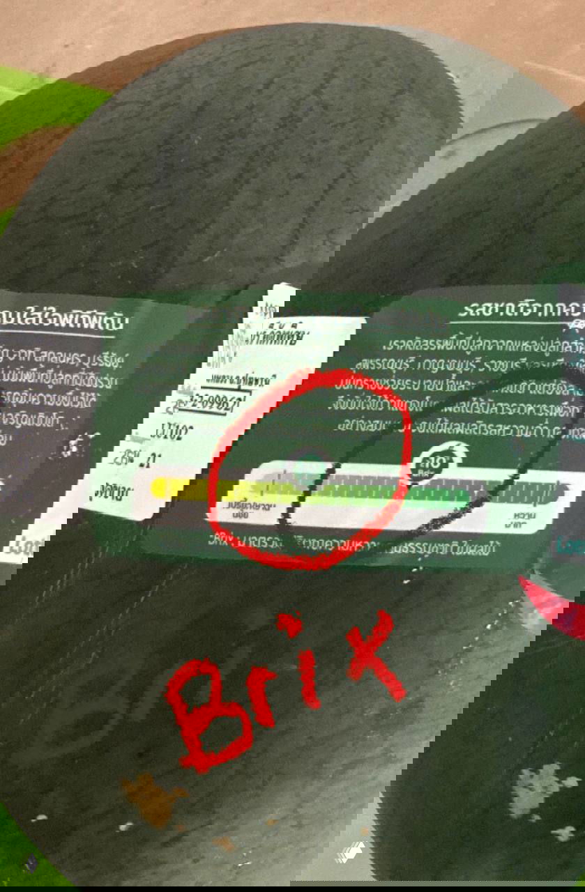 Крупный план этикетки арбуза с графической шкалой Brix, где красным отмечен уровень около 10 градусов — как указано на упаковке.