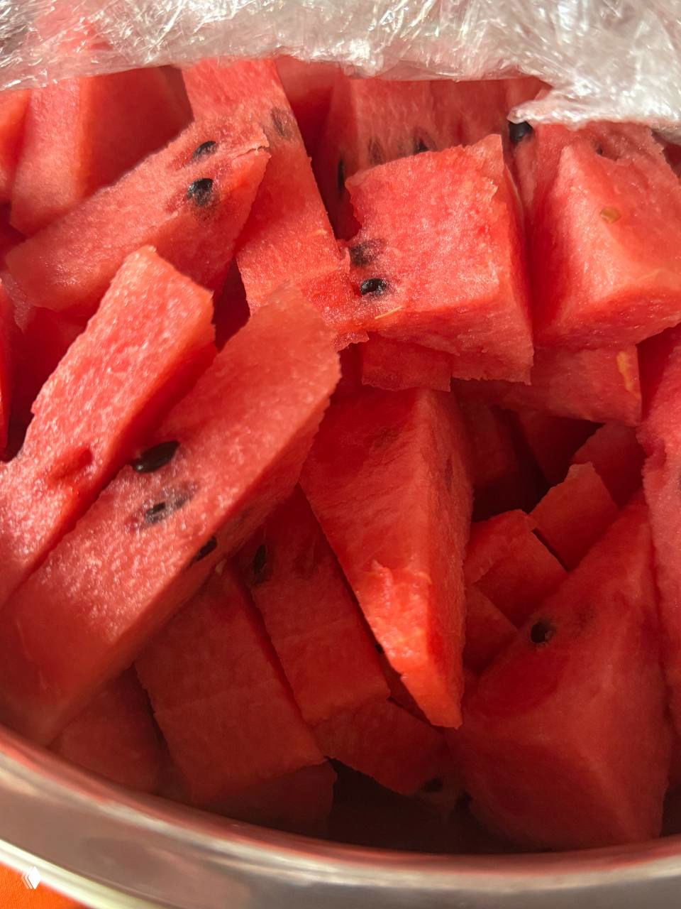 Нарезанный кубиками арбуз в миске: сочные ярко-красные кусочки с семечками, готовые к подаче и охлаждённые для освежения.