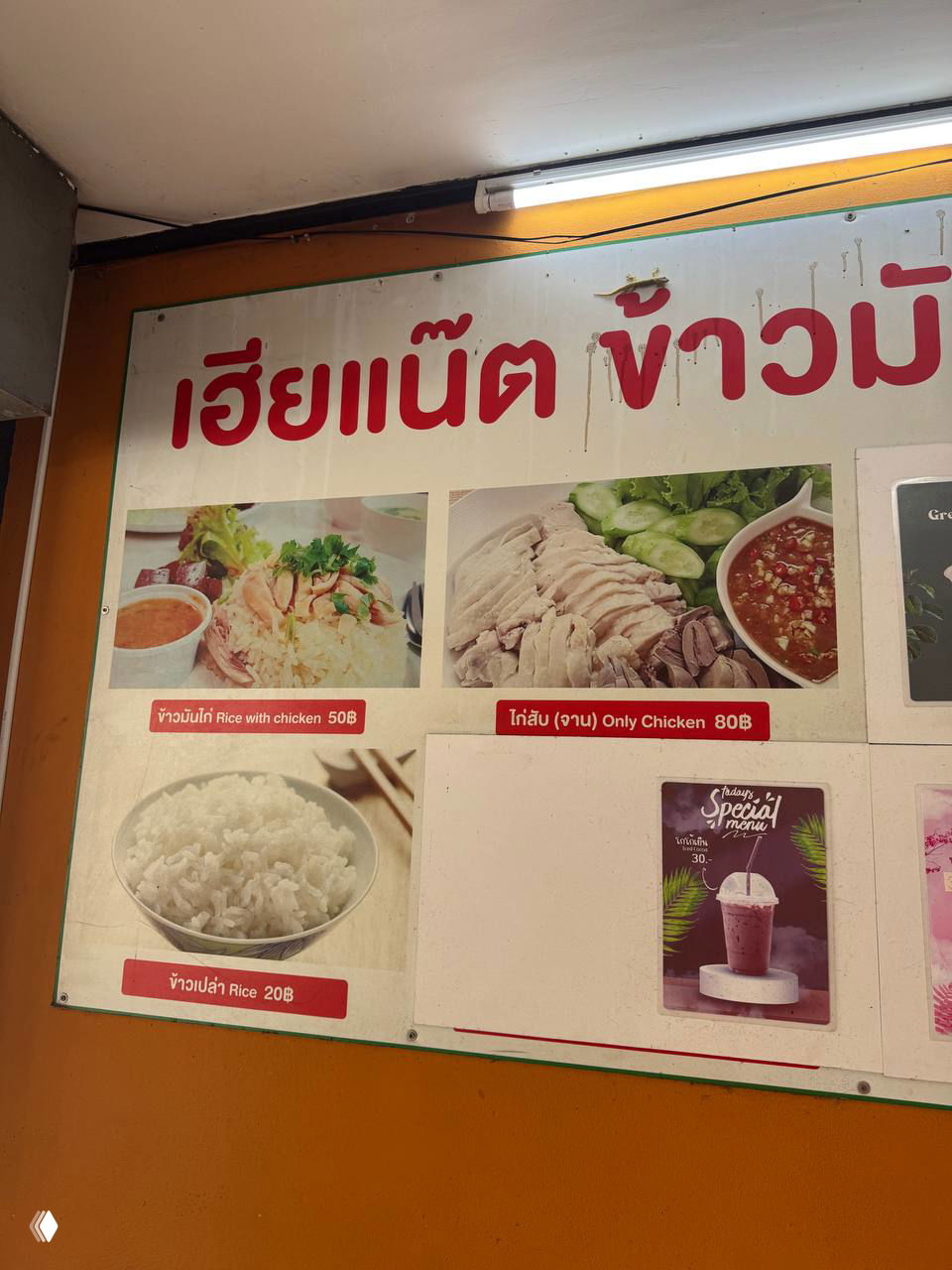 Меню на стене кафе с фотографиями хайнаньского риса, ценой 50 бат за порцию и вариантом только курицы за 80 бат, подписи на тайском и английском.