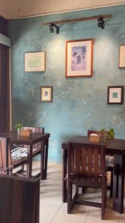 Интерьер Art cafe by June: бирюзовая текстурная стена с картинами, деревянные столы и стулья, спокойная уютная атмосфера для завтрака.