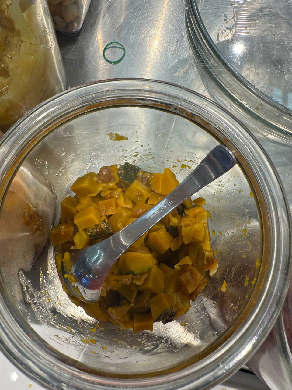 Банка с тёмно-коричневыми сладкими кусочками одного из экзотических топпингов для кокосового мороженого, вид на прилавок