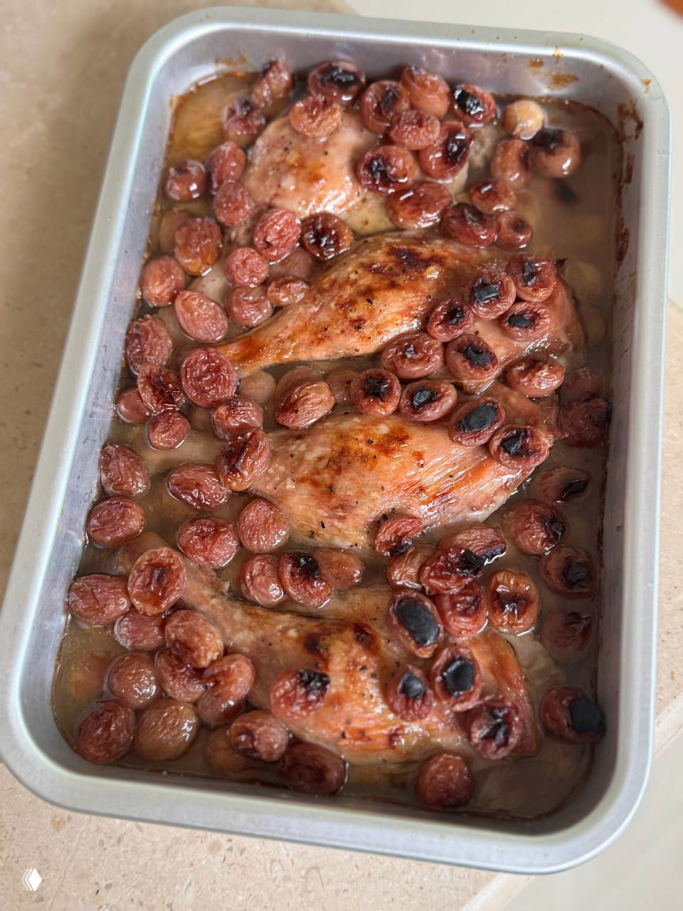 Запечённые утиные ножки в металлической форме с карамелизованным красным виноградом, золотистая корочка и подлива в противне.