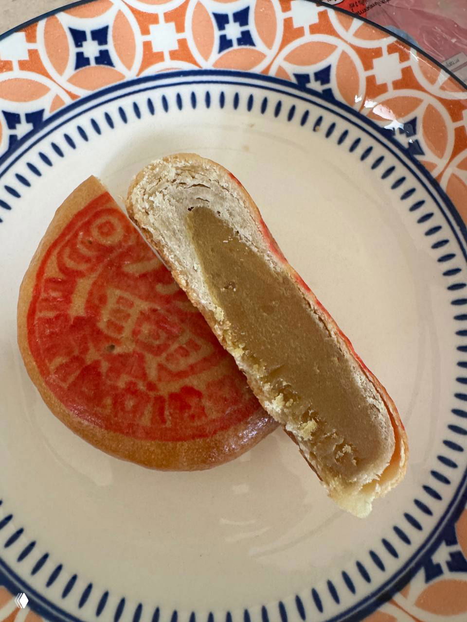 Разрезанный mooncake на тарелке: видно плотную бобовую начинку густой текстуры и слоистую песочную оболочку, вид сбоку.