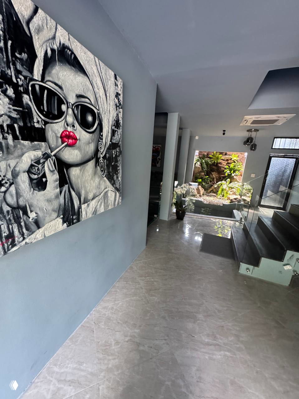 Коридор и большая картина в интерьере ресторана ACQUA: современный холл с серыми стенами и дизайнерской картиной с акцентом на красные губы.