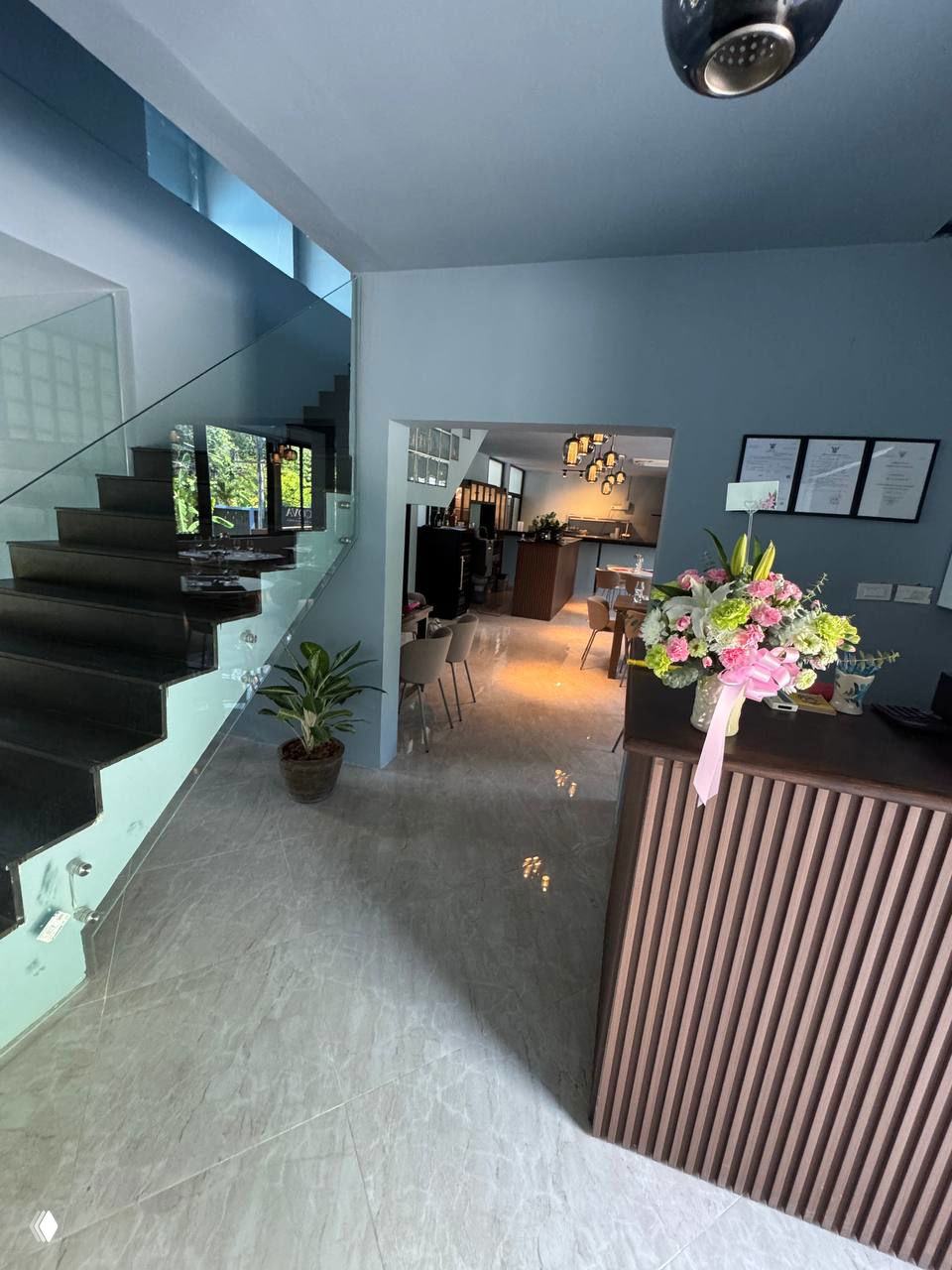 Вид внутреннего помещения ACQUA: лестница, стеклянные перила и вход в основную зал выдающие свет и столики, фото сделано под углом.