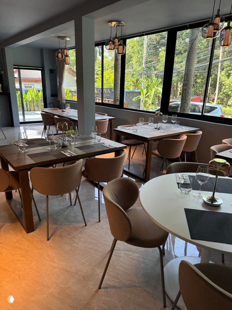 Зал ресторана ACQUA с сервировкой: столы у окон, стеклянная посуда, современная мебель — дневное освещение и вид на улицу.