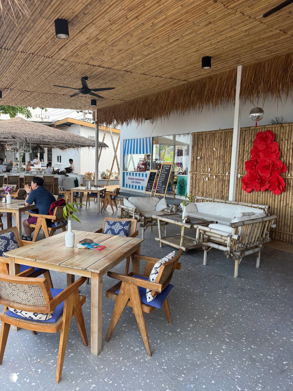 Открытая лаунж-зона с бамбуковым оформлением, деревянные столы и диваны под крышей — уютное место для родителей и семейного обеда.