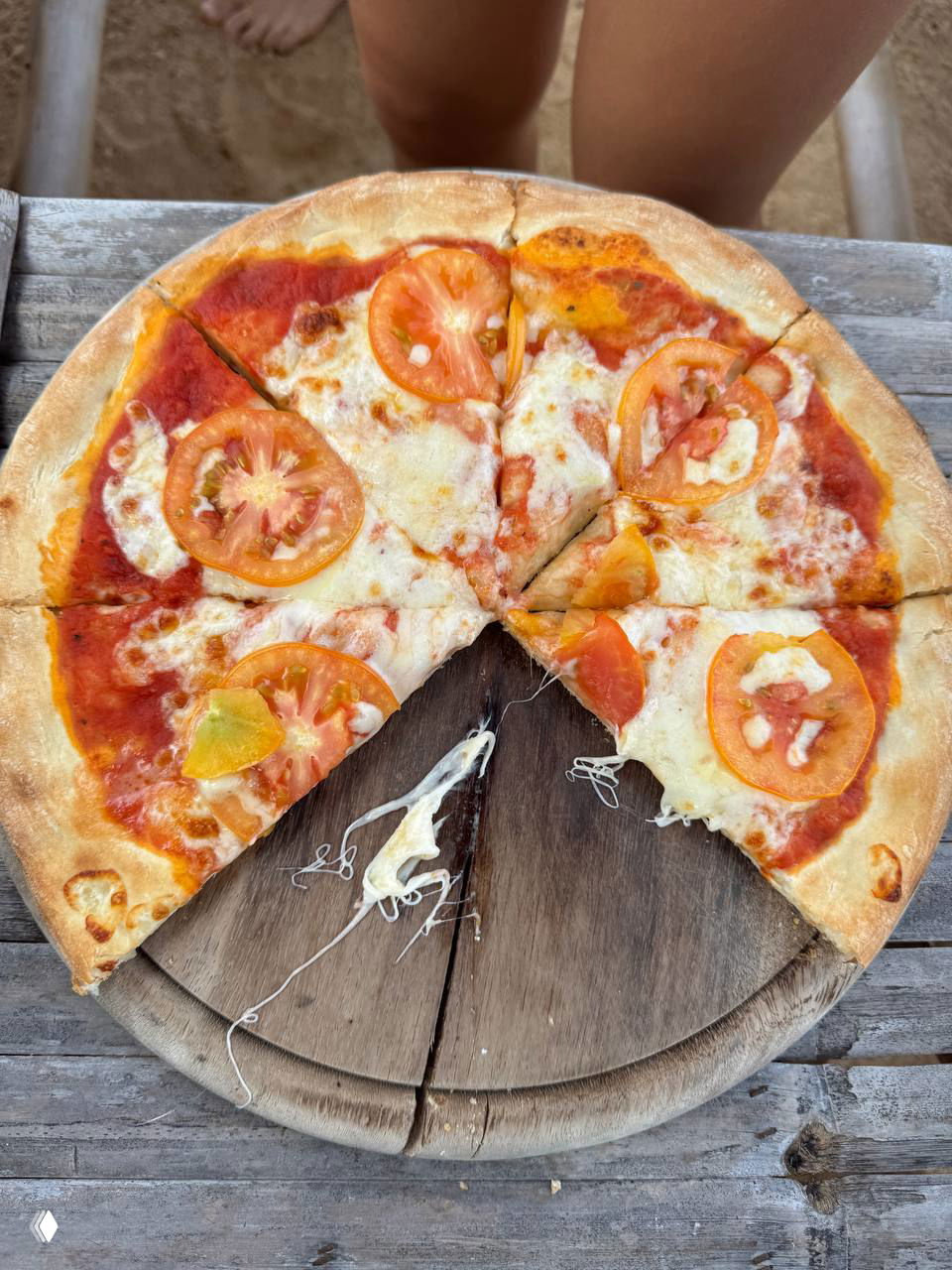Пицца «маргарита» на деревянной доске: ломтики с томатами и расплавленным сыром, фото блюда, поданного на пляжном столе — быстрая подача.