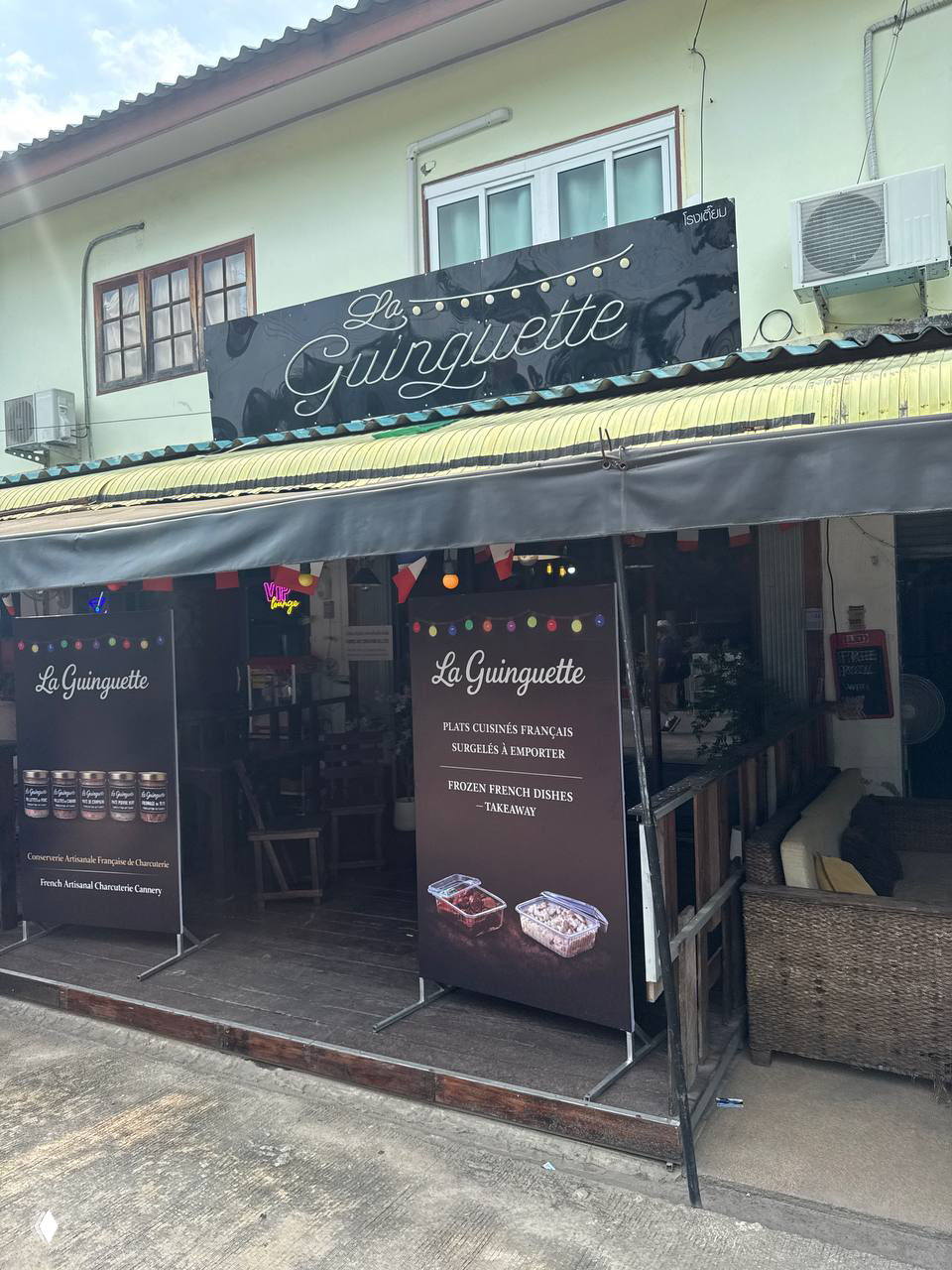 Фасад магазина La Guinguette в Ламай: вывеска, баннеры с логотипом и изображениями замороженных блюд на входе на уличной витрине.