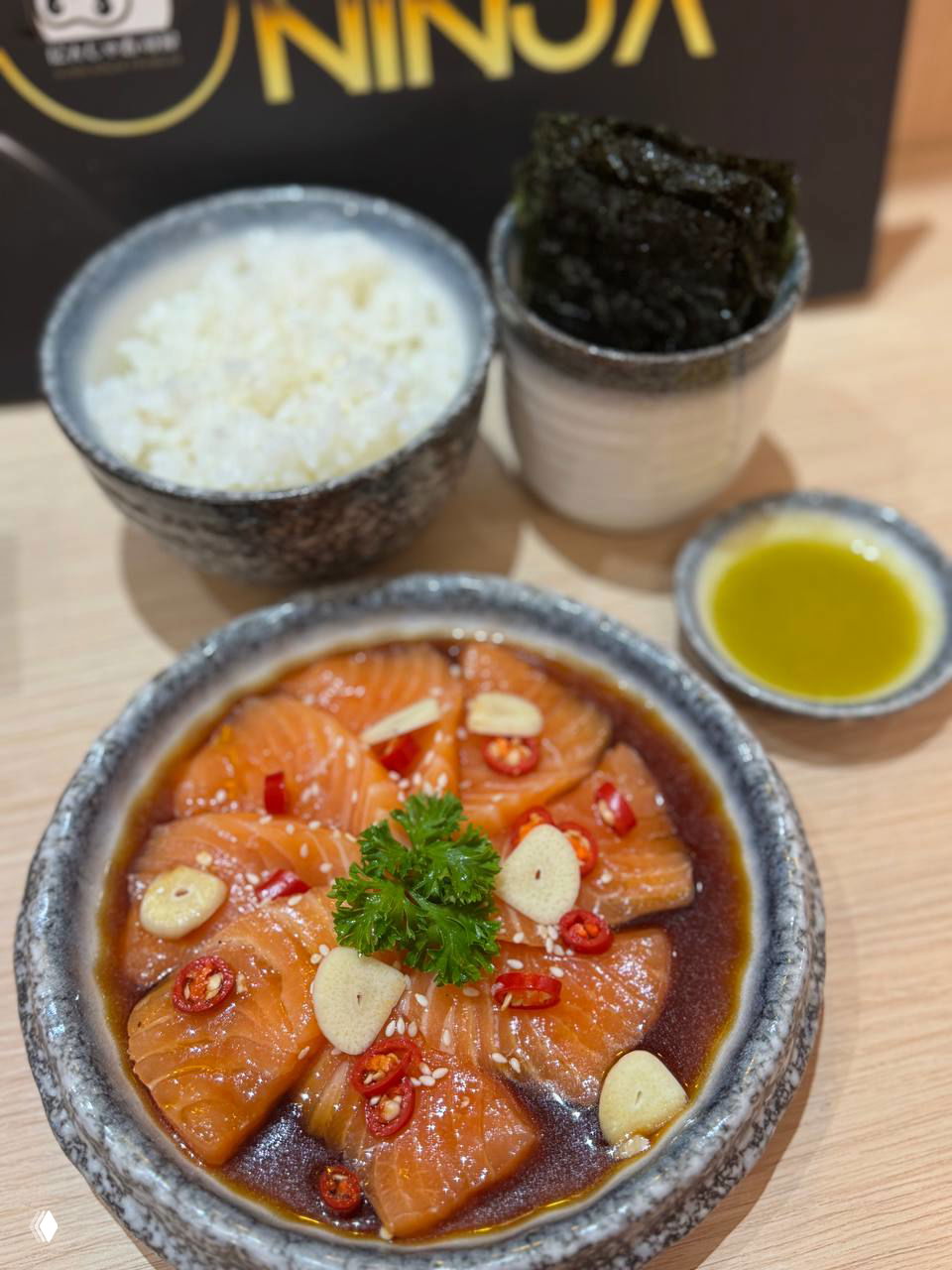 Маринованный лосось в миске с соусом, мисочка с рисом и стопка нори на столе — комплект Pickled salmon Ninja sauce set в точке Sushi Ninja в Лотусе.