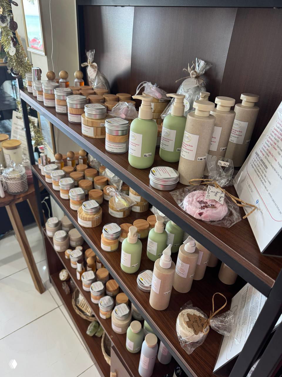 Полка с небольшими баночками и тюбиками натуральной косметики: кремы, скрабы и средства в однотонной упаковке с деревянными крышками.