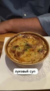 Порция классического лукового супа в керамической форме с расплавленным сыром сверху — традиционный элемент французского сета в ресторане.